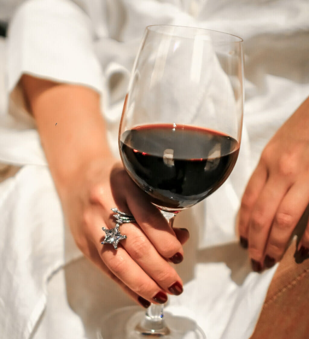 holding red wine with wine fingernails and shooting star ring