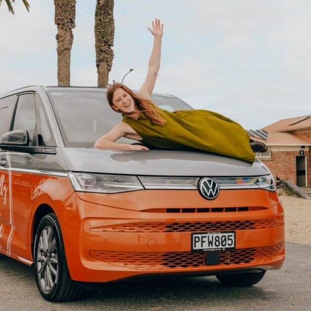 Ethically Kate laying on top of orange PHEV Volkswagen Car