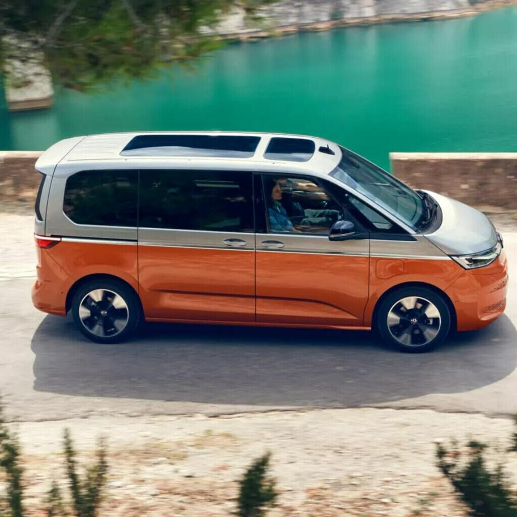 Orange Volkswagen PHEV Van driving in front of lake