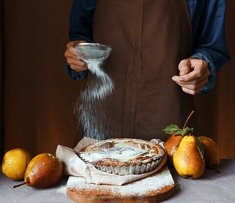 Woman sprinkling sugar on pie