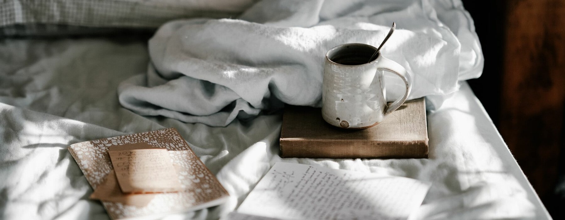A mug and books on a bed