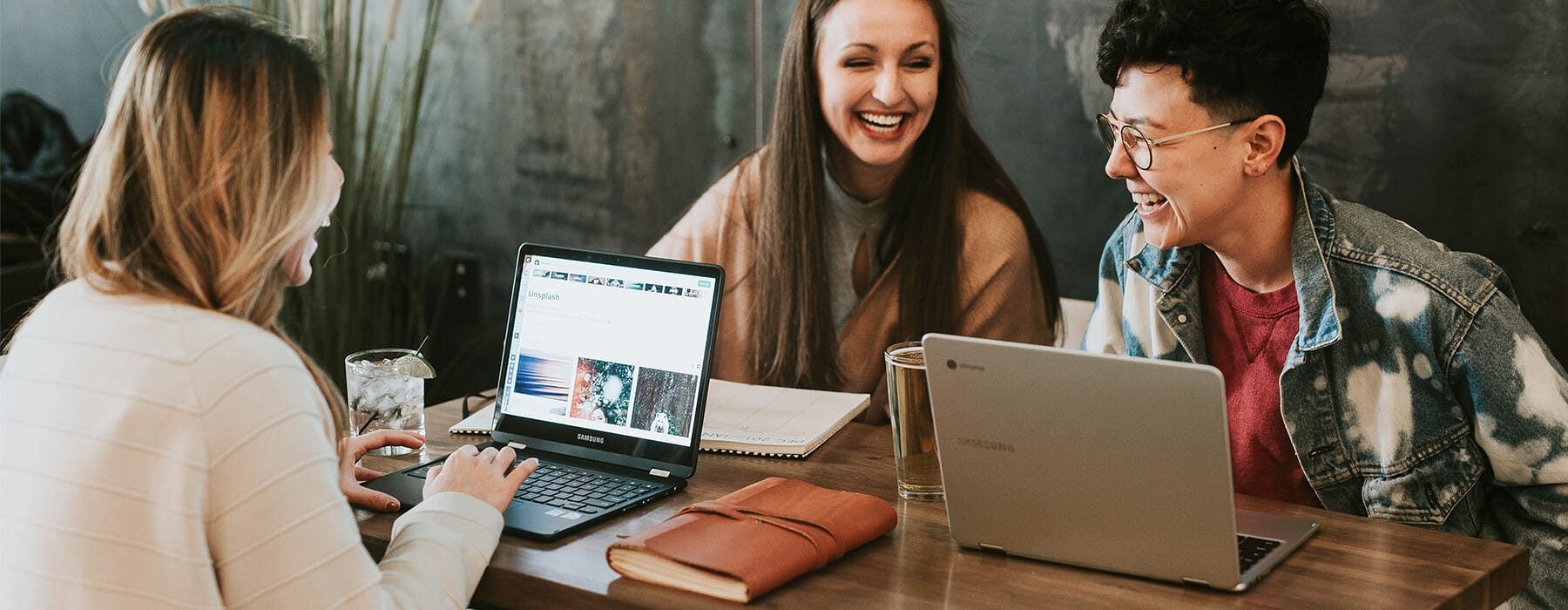 Three women sitting around a table with laptops