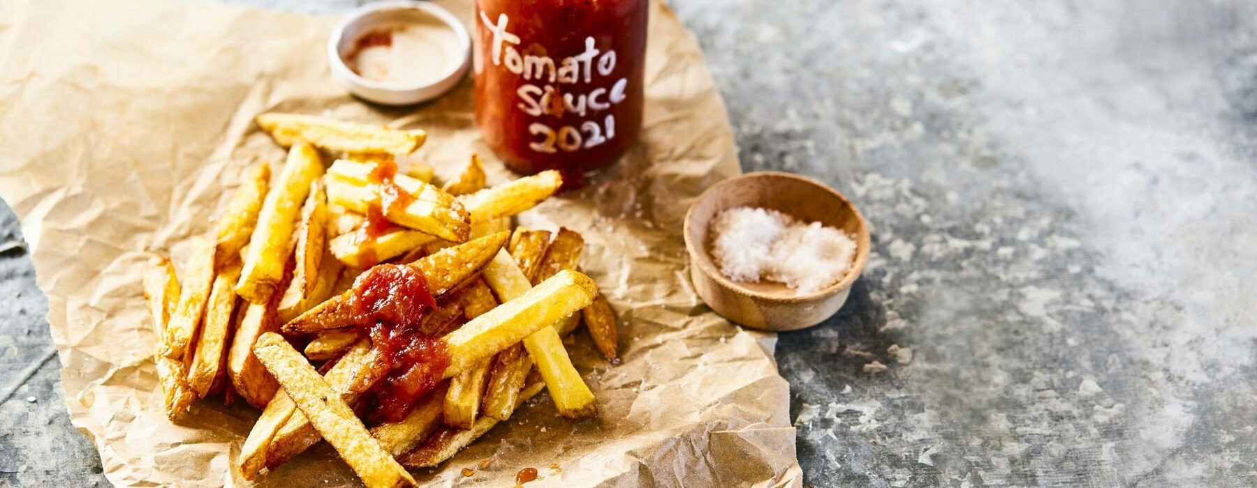A bottle of tomato sauce surrounded by chips