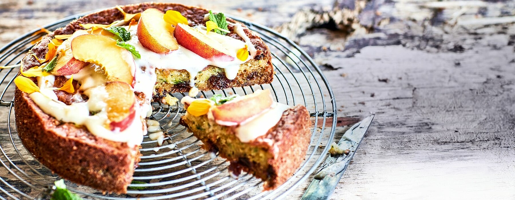 Courgette and raisin cake on a wooden table surrounded by yellow flowers
