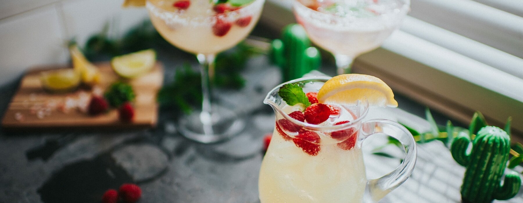 Stylishly presented margherita cocktails, in a kitchen environment with a jug, and dressed with fruit.