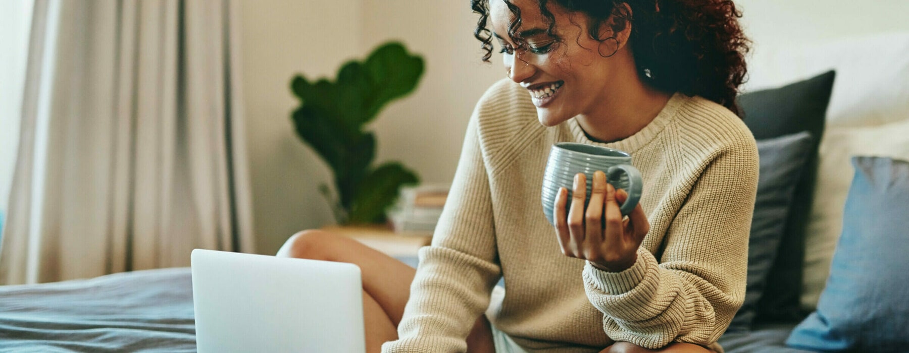 Shot of an attractive young woman drinking coffee while using her laptop