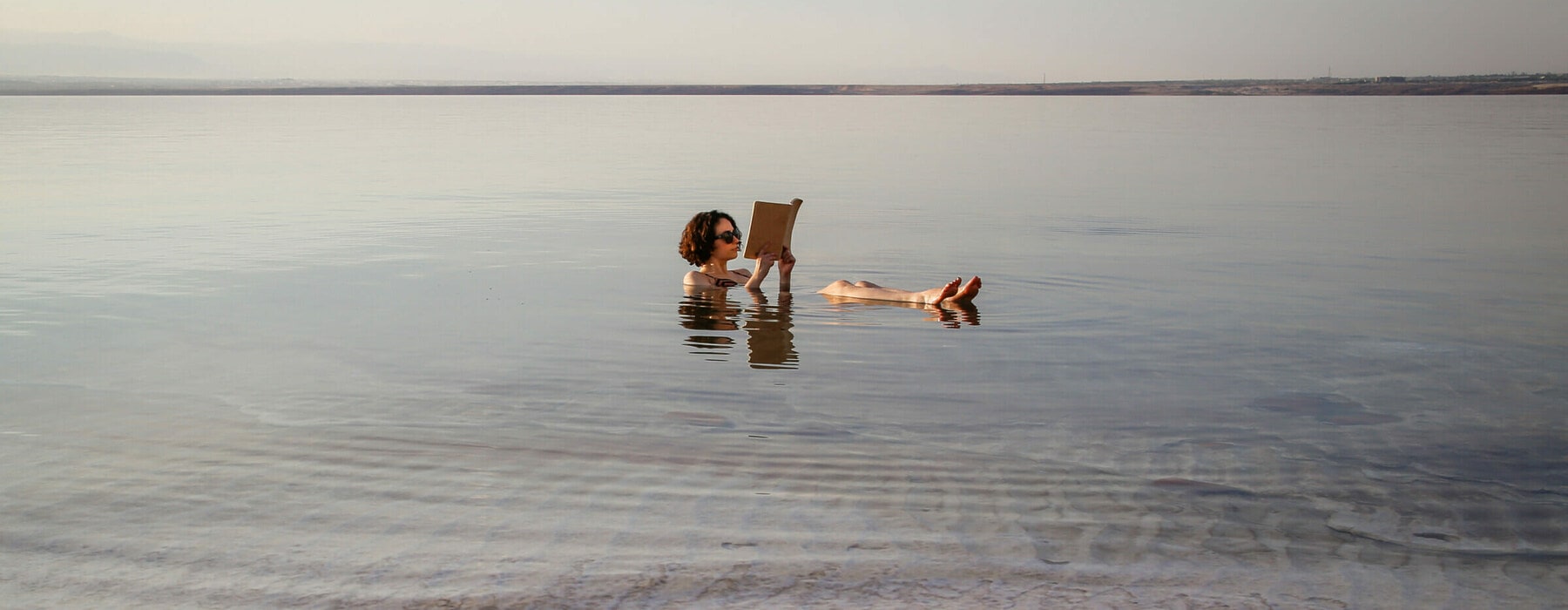 A girl reading book in salt lake dead sea in Jordan