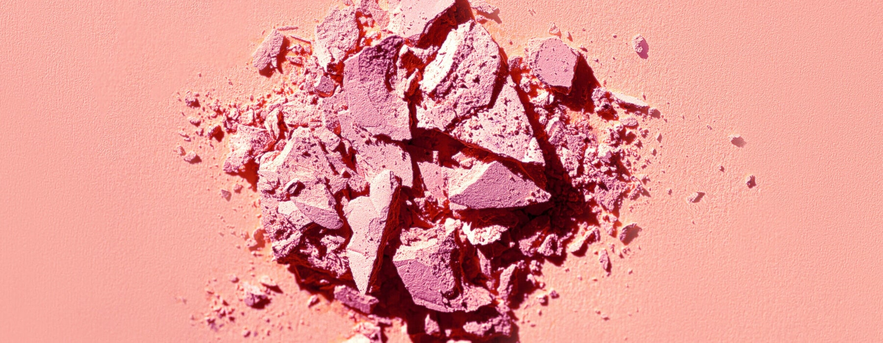 Eye shadow matte pink sand texture background. Beauty product in natural colours. Copy space, close up.