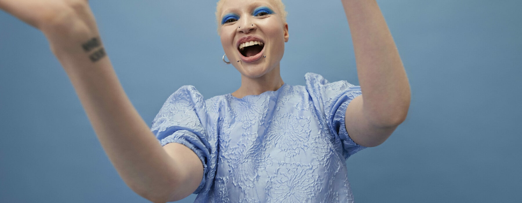 Portrait of happy albino young woman enjoying while dancing against blue background