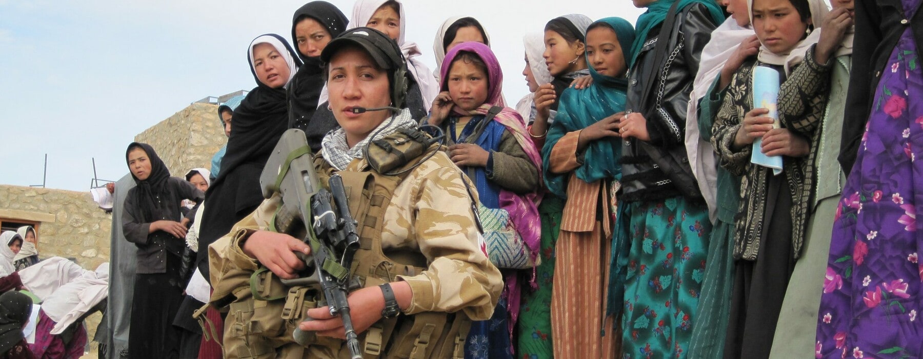 A woman holding a gun standing in front of several children