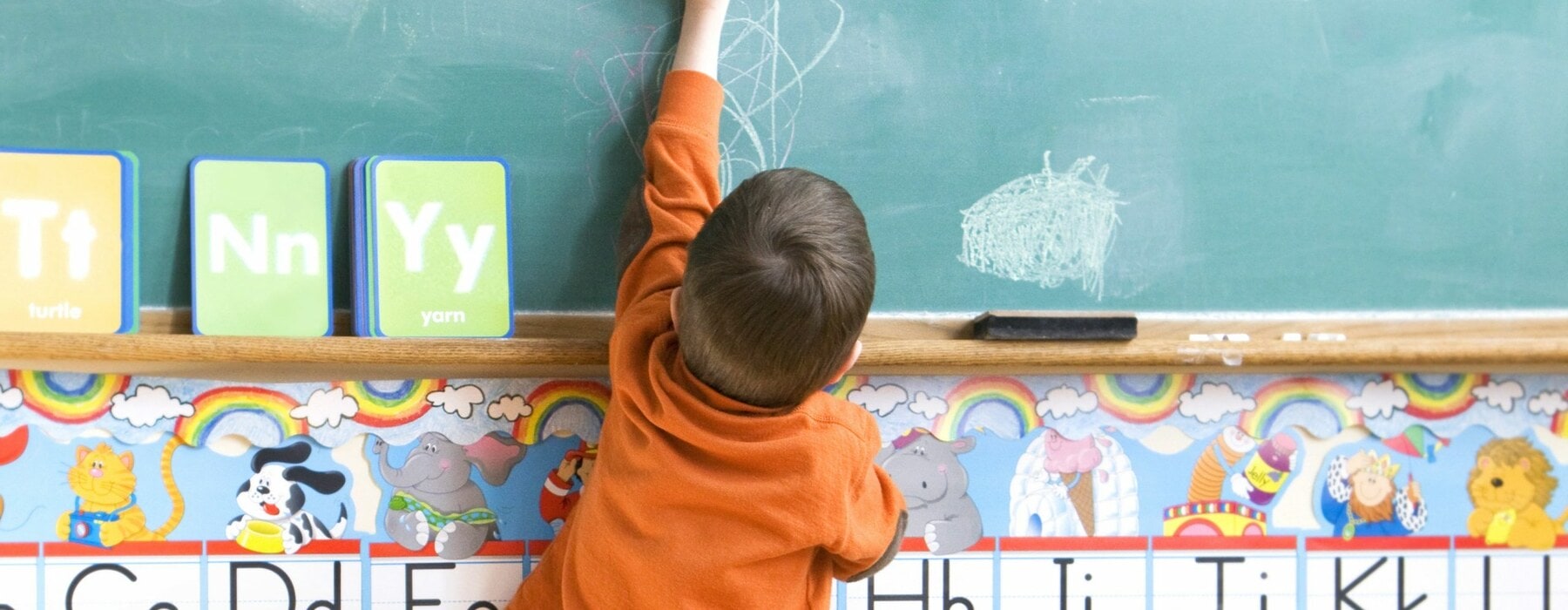 Little boy drawing on chalkboard at school