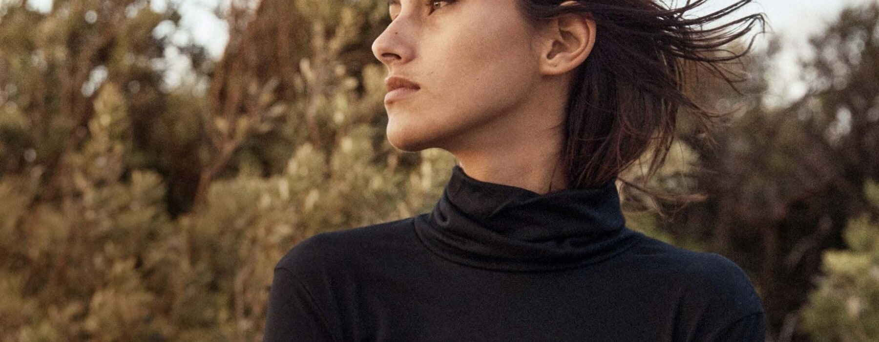 Woman wearing black turtleneck top looking out into the distance
