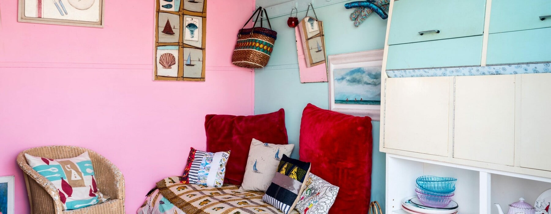 Pink and blue painted bedroom with an assortment of second-hand decor items, furniture and plates