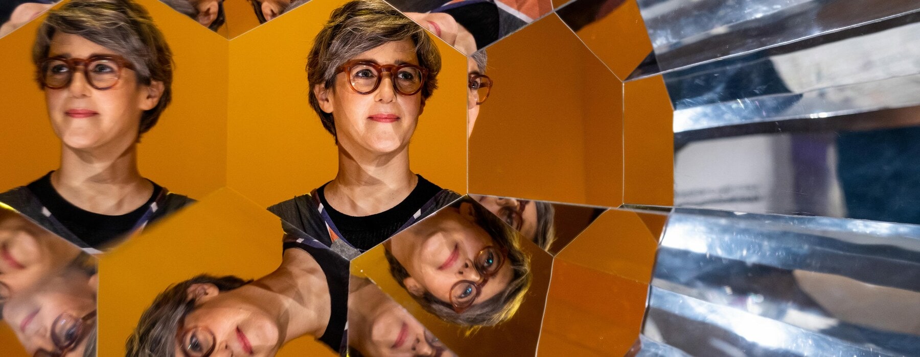 Kaleidoscope reflections of Lizzie Bisley wearing glasses and a black top