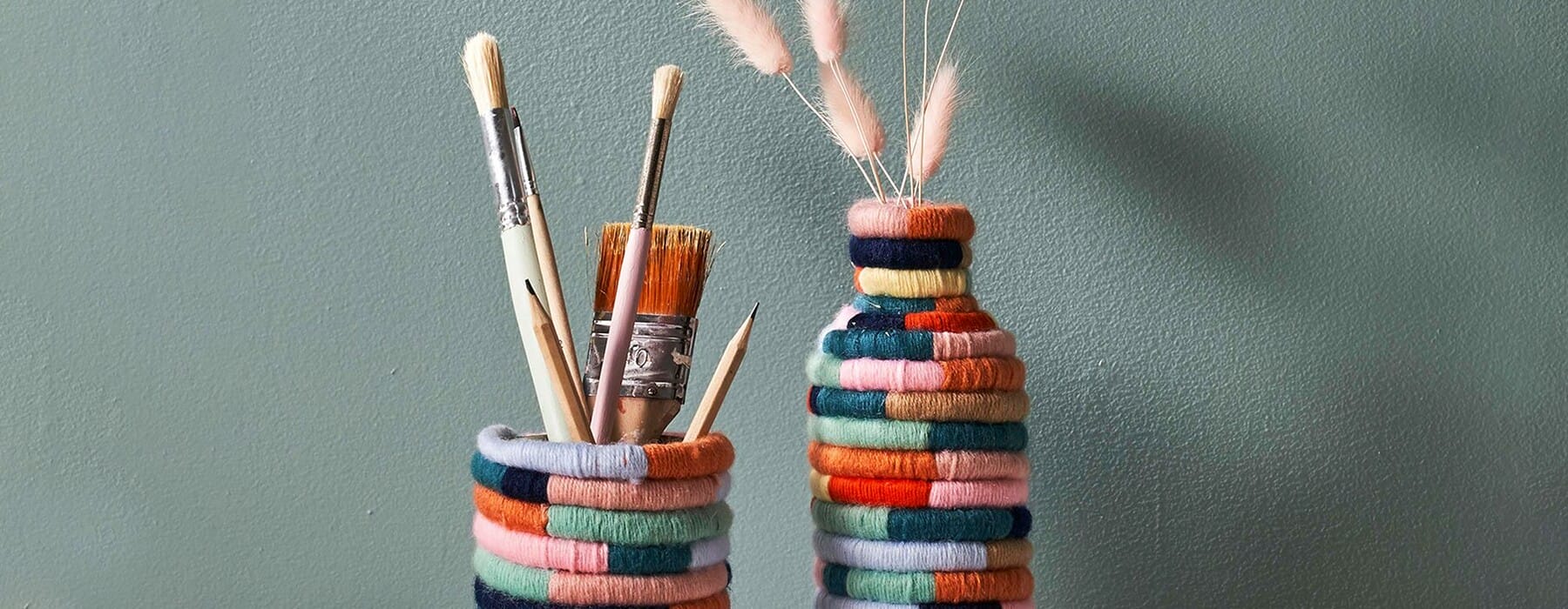 Bottles wrapped in rainbow wrap sitting against green wall