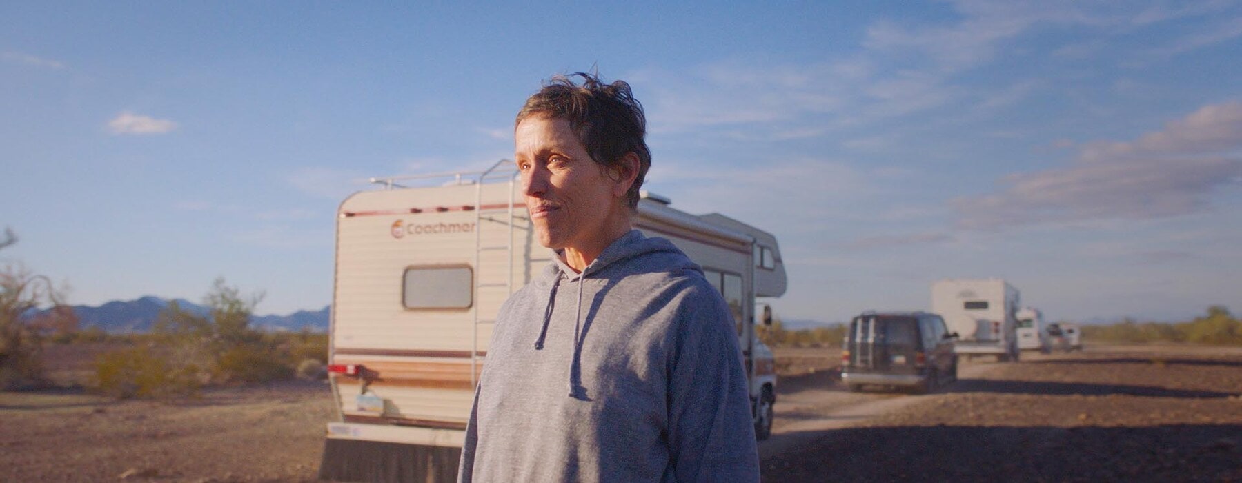 Frances McDormand in Nomadland standing outside an RV