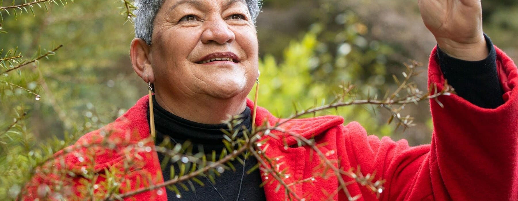 Donna Kerridge standing in garden wearing a red coat and black top