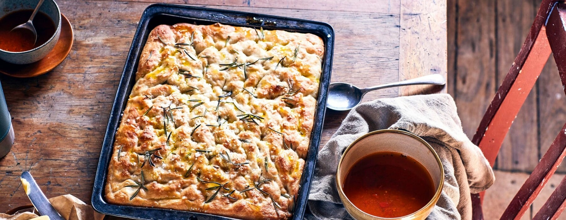 A black tray with rosemary and sea salt focaccia set on a brown table