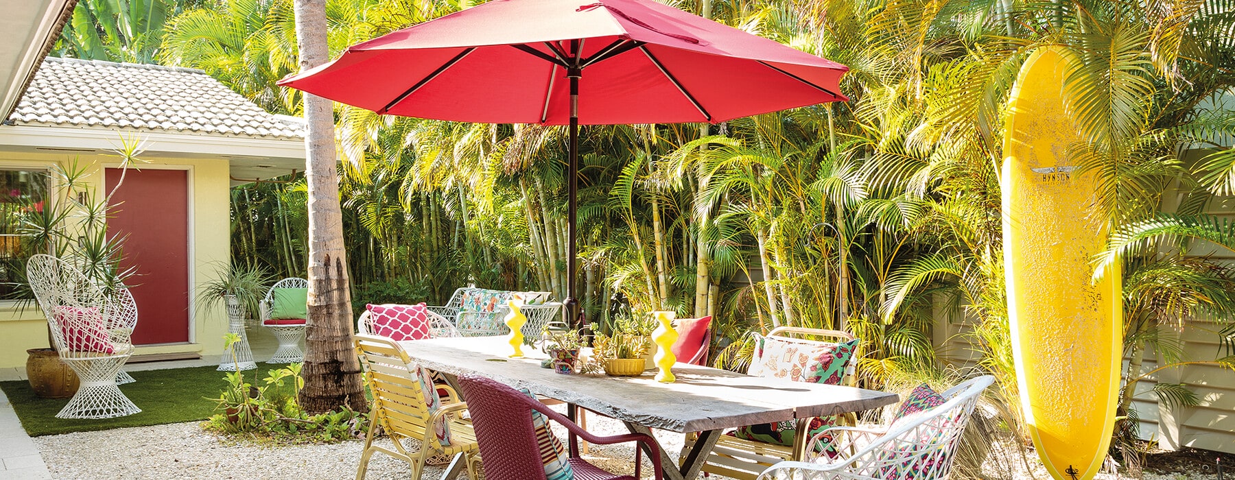 Outside dining area with yellow surfboard and red umbrella
