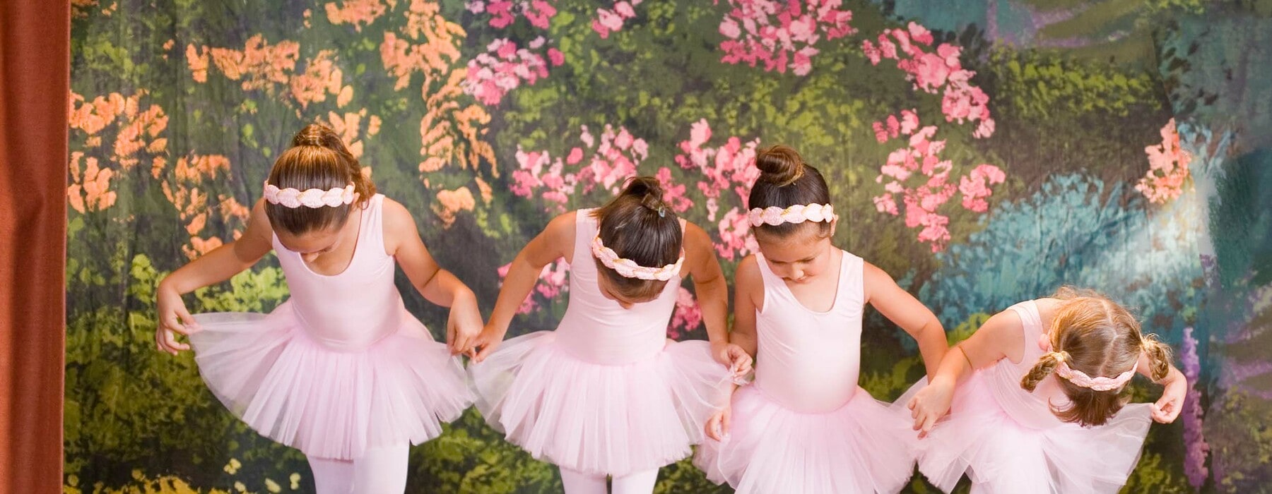 a group of little girls in pin leotards, tutus and tights and doing ballet
