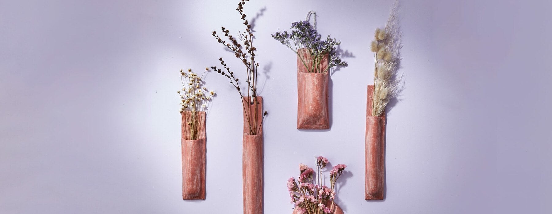 Terracotta wall vases hanging on purple wall