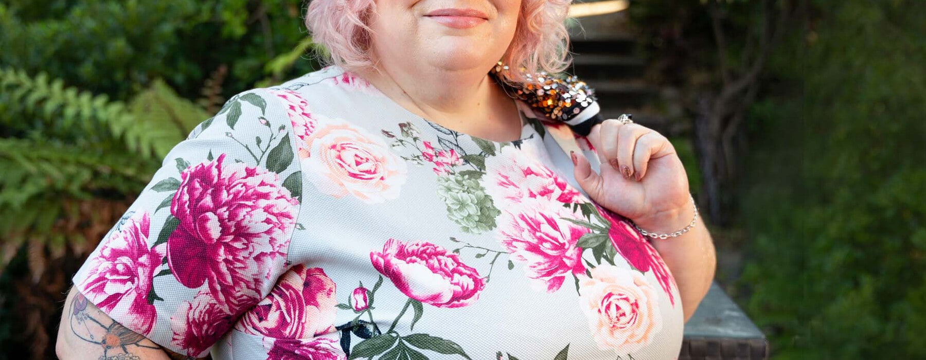 a woman with short pink hair in a floral dress
