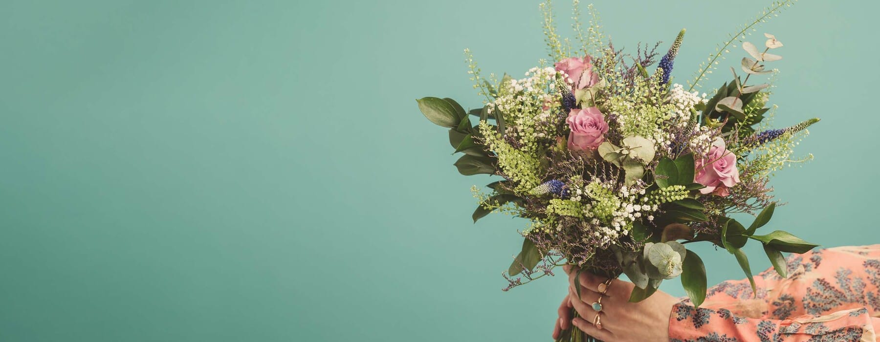 Woman holding a big bouquet of flowers, arms only