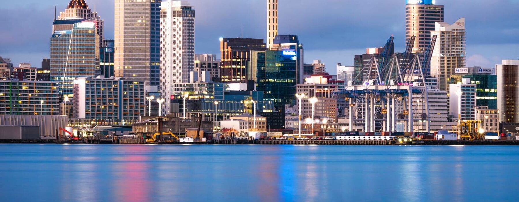 Auckland's CBD seen from across the water at dawn, with the Sky Tower in the centre of the image.