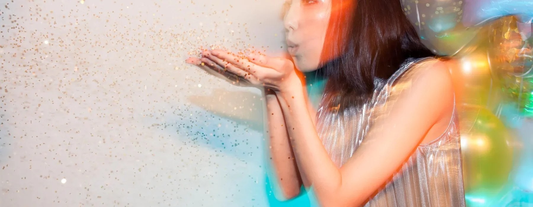 girl blowing colourful confetti dust