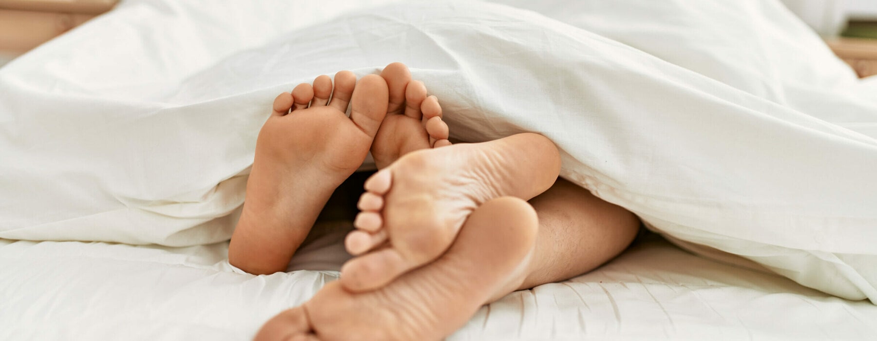 Couple,Feet,Under,Sheets,On,The,Bed,At,Home.