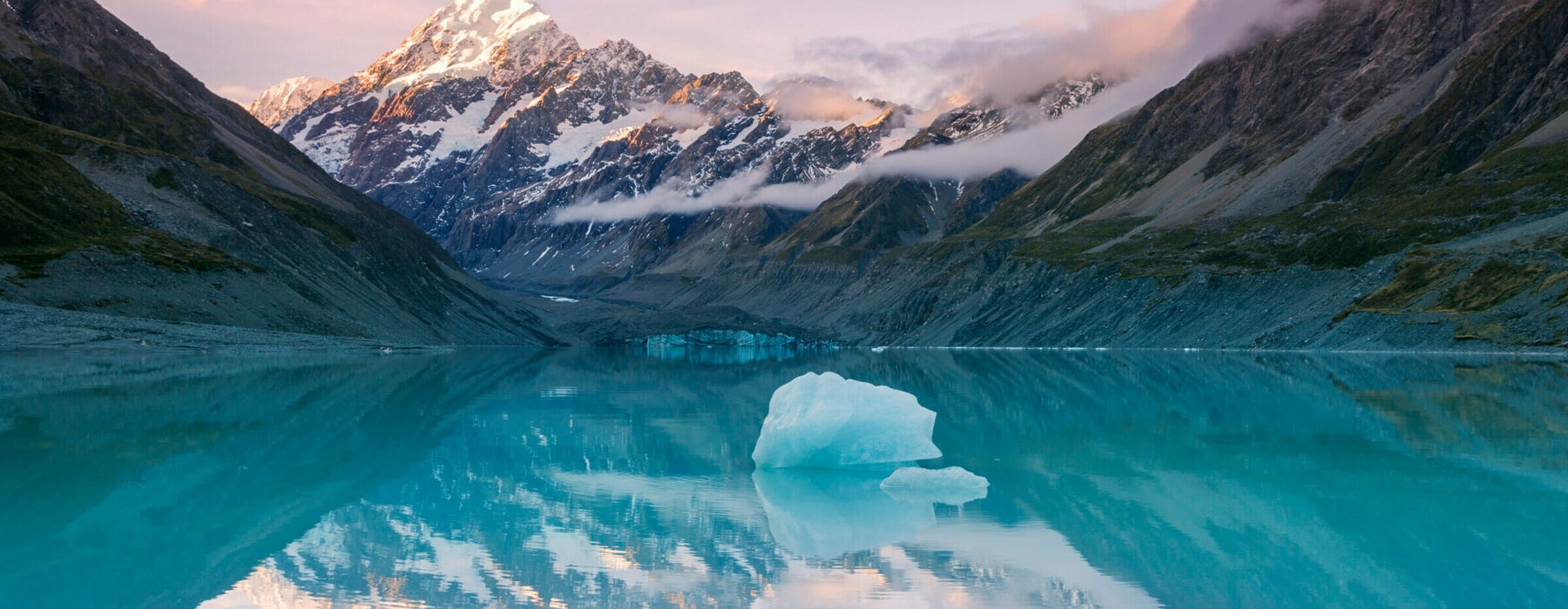 Snowcapped peak of mount Cook reflecting in still lake with iceberg at sunset, Aoraki mount Cook National park, Canterbury region, South Island, New Zealand.