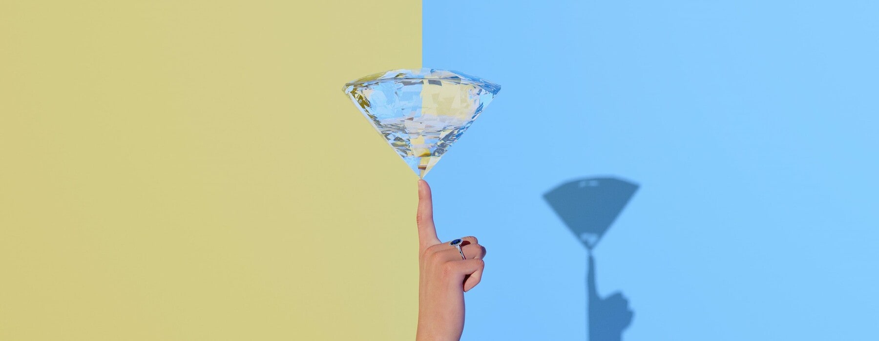a diamond balancing on a finger in front of a blue and yellow background